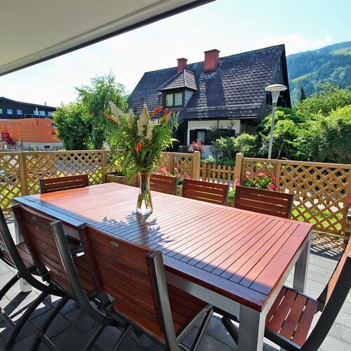 Outdoor balcony dining area with wooden table and chairs