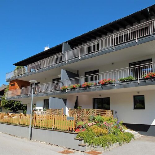 Modern three-story apartment building with balconies and flowers