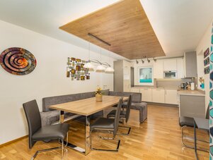 Bright open-plan dining area with wooden table and kitchen.