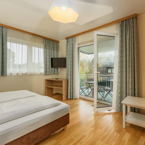 Hotel room with double bed, balcony doors, and seating area.