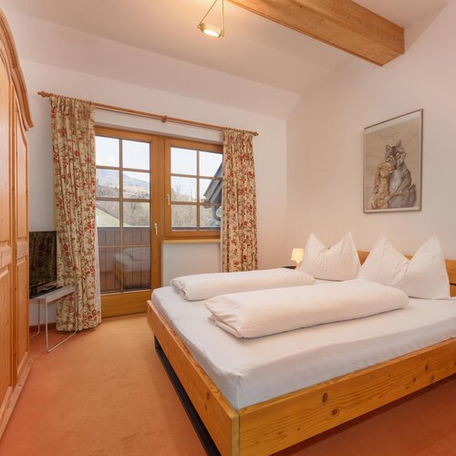 Cozy wooden bedroom with large bed, wardrobe, and floral curtains