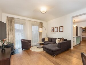 Living room with dark sectional sofa, armchair, and large windows