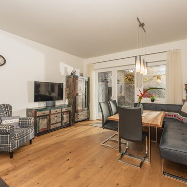 Living room with dining table, sofa, plaid armchair, and rustic sideboard