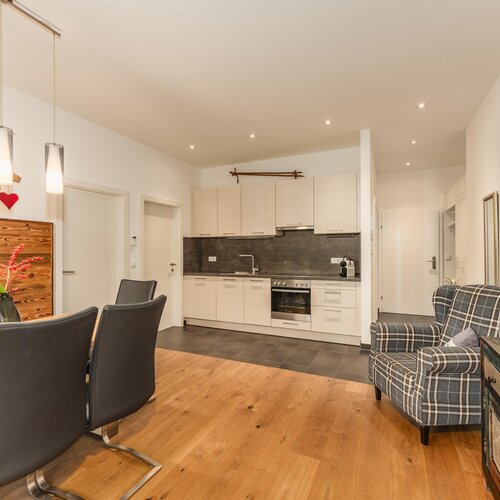 Open-plan kitchen and dining area with wood table and black chairs