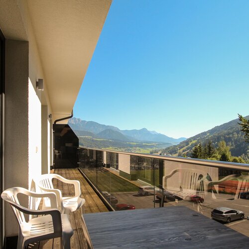 Balcony with plastic chairs and table overlooking mountains