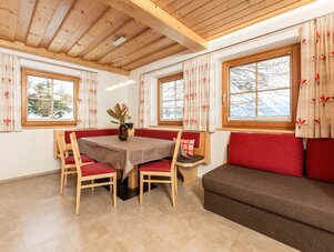 Cozy dining area with wooden ceiling beams and red cushioned seating