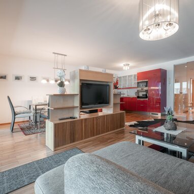 Open-plan living room with red kitchen and dining area | © TIEBER