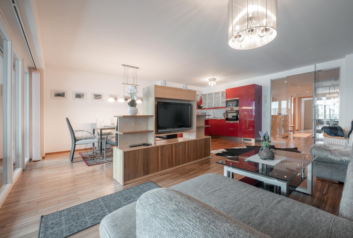 Open-plan living room with red kitchen and dining area | © TIEBER