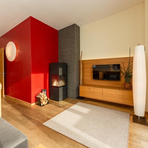 Modern living room with red accent wall, fireplace and TV