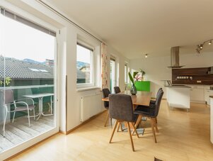Bright open-plan dining area with kitchen and balcony