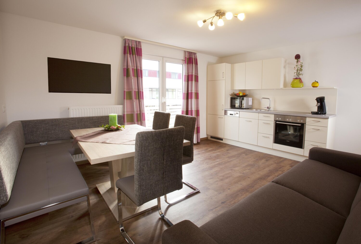 Open-plan living area with dining table, seating, and white kitchen