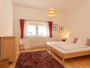 Bright wooden bedroom with a double bed and red curtains