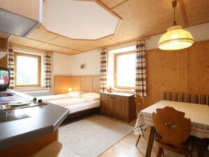 Cozy wooden hotel room with bed, table, and kitchenette.