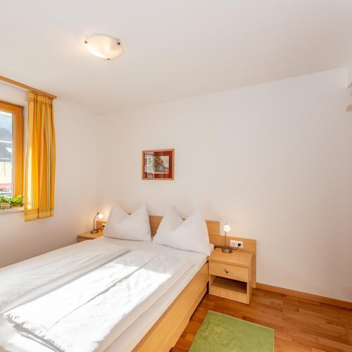 Bright bedroom with a double bed, pillows, and wooden furniture