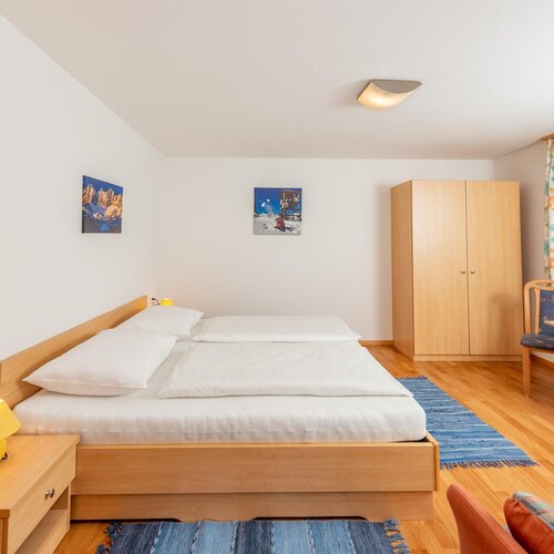 Bright hotel room with large bed, wardrobe, and desk