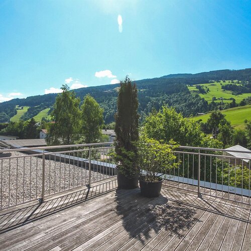 Rooftop wooden deck with potted plants and hillside view