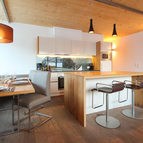 Open-plan kitchen and dining area with wooden ceiling and island | © SCHLADMING-APPARTEMENTS