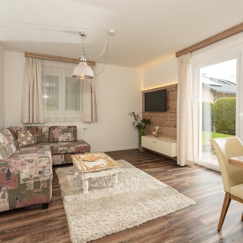 Bright living room with patterned sofa, coffee table, and TV