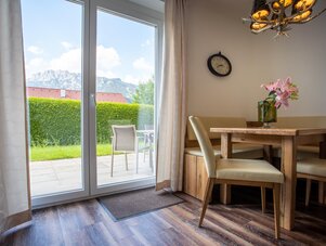Dining area with wooden table and chairs by glass doors to patio