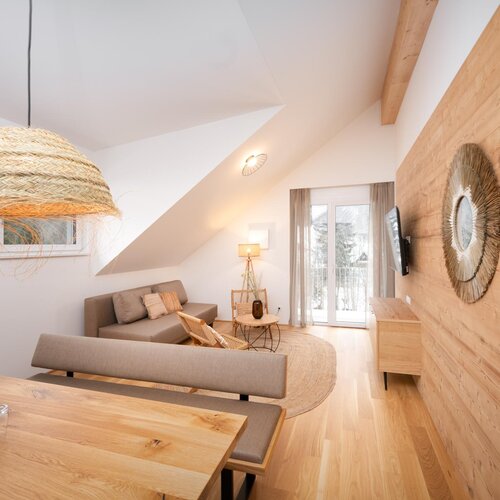 Cozy living room with wood-paneled wall, beige sofa, and wicker pendant lights