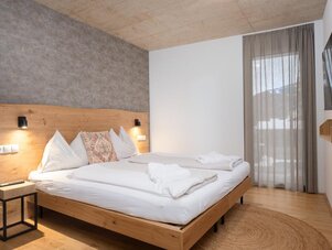 Hotel bedroom with large wooden bed and white linens