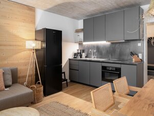Modern open-plan kitchen with grey cabinets and black refrigerator