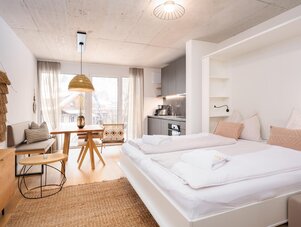 Bright open-plan studio with bed, dining table, and kitchenette