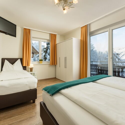 Bright hotel room with two beds and balcony view