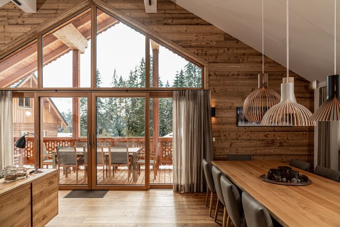 Cozy wooden cabin dining area with large glass doors to deck.