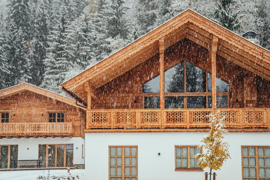 Snowy wooden chalet with large balcony and trees