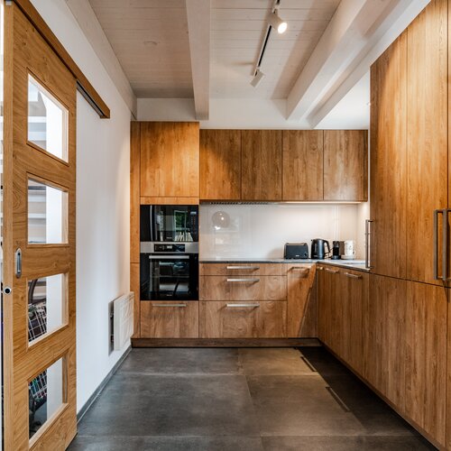 Modern kitchen with wooden cabinets, built-in oven, and dark floor