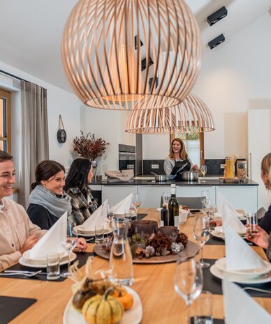 Group of people dining around a long table in bright kitchen