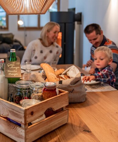 Family at dining table with food basket and label Guten Morgen.