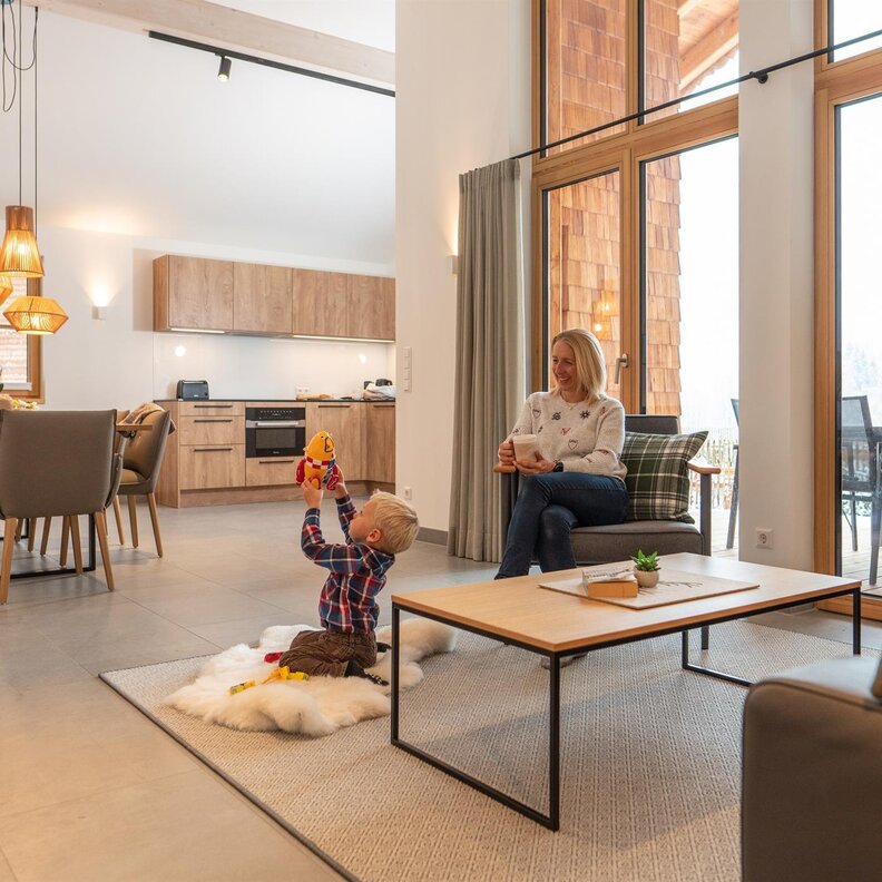 Child playing with toy on fluffy rug as woman sits nearby