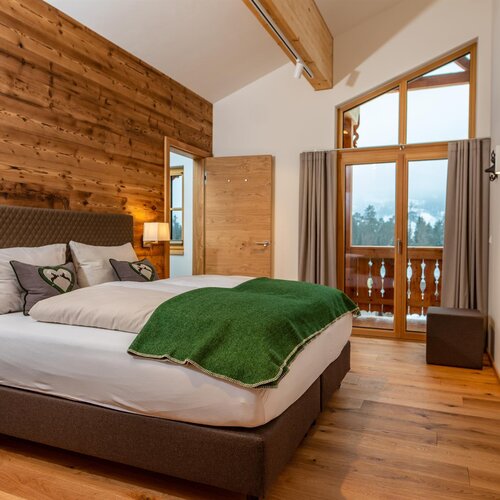 King-size bed in a wood-accent cabin bedroom with balcony