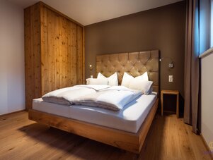Wooden platform bed with tufted leather headboard in warm bedroom