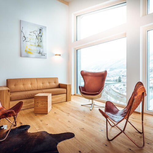 Bright living room with leather chairs and large windows overlooking snowy mountains