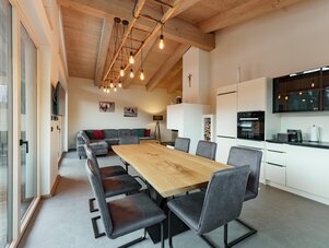 Open-plan kitchen and dining area with wooden beams and glass doors