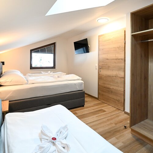 Hotel room with two beds, wardrobe, and TV