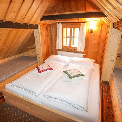 Cozy attic bedroom with wood paneling and a bed
