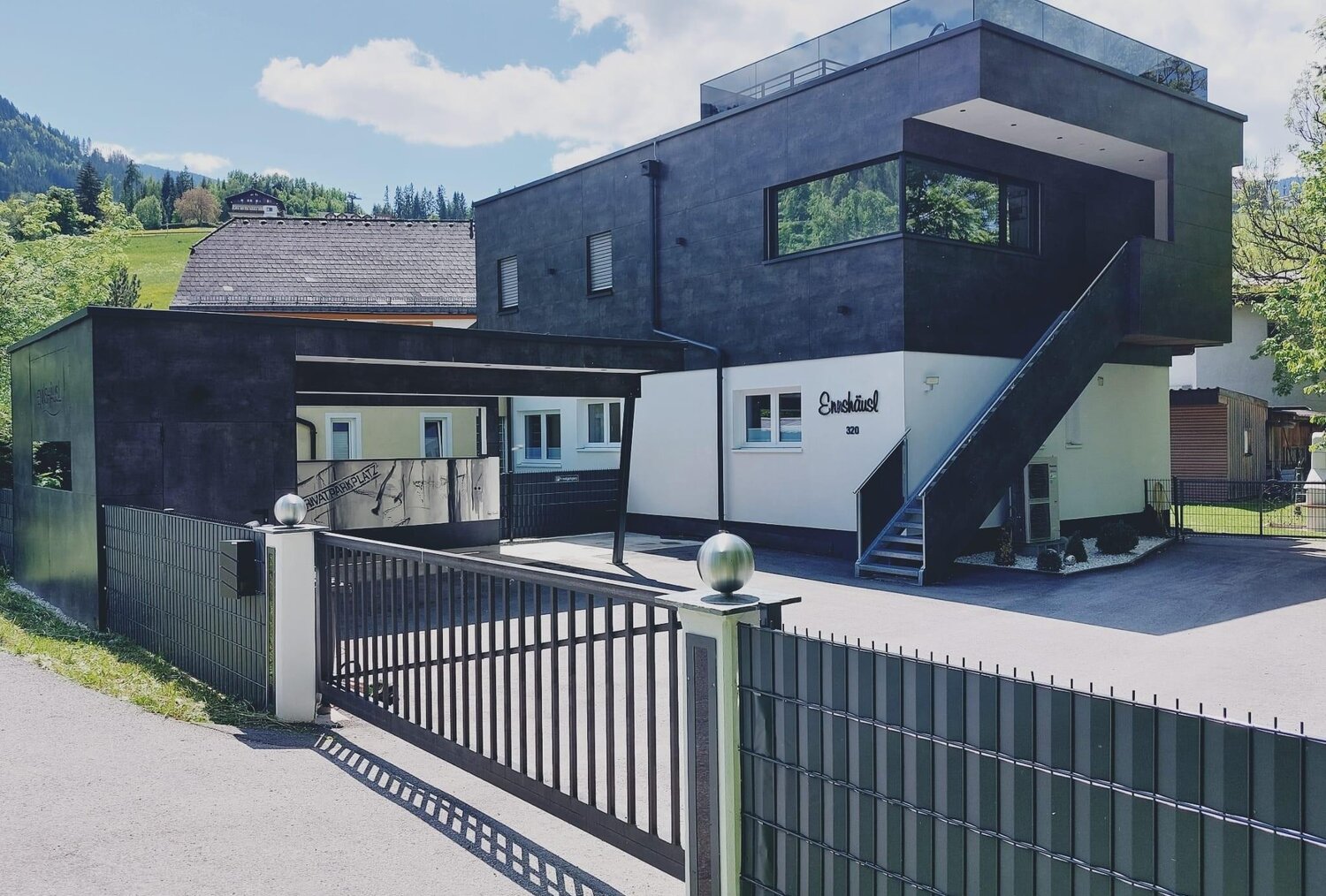 Modern two-story building with black exterior and gated entrance