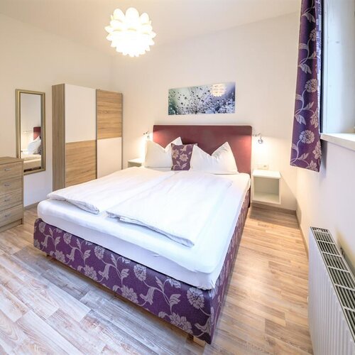 Bright modern bedroom with purple floral-patterned bed base