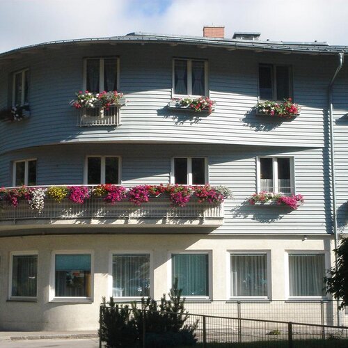 White curved apartment building with balconies and flowers