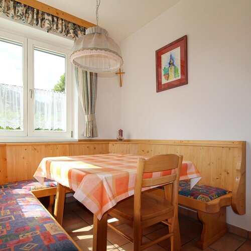 Corner dining nook with wooden benches and orange checkered tablecloth