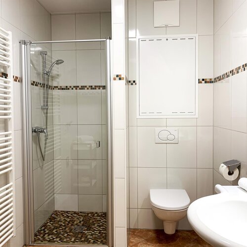 Bright bathroom featuring glass shower, toilet, and sink
