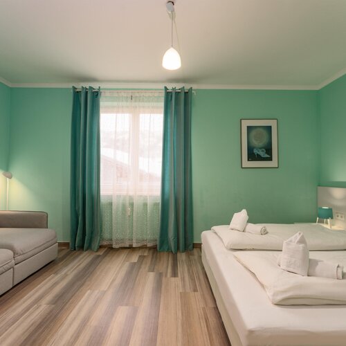 Hotel room with teal walls, double bed, and sofa.