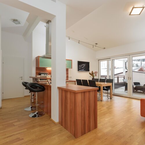Open-plan living area with kitchen island, dining table, and balcony doors