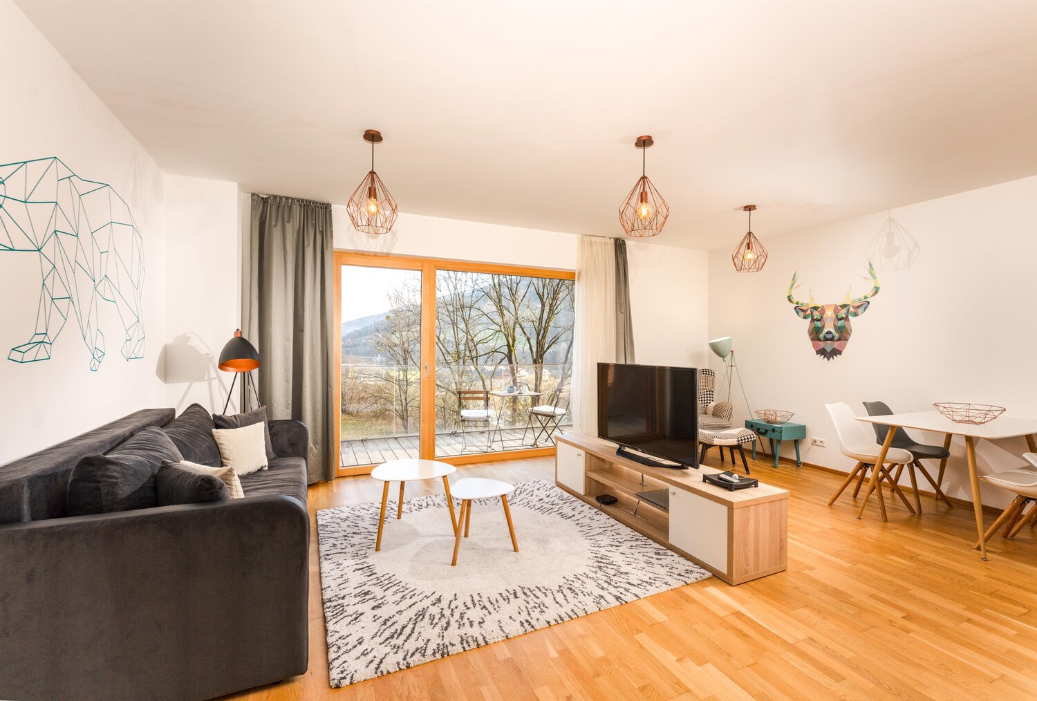 Modern living room with grey sofa, glass doors, and geometric wall art