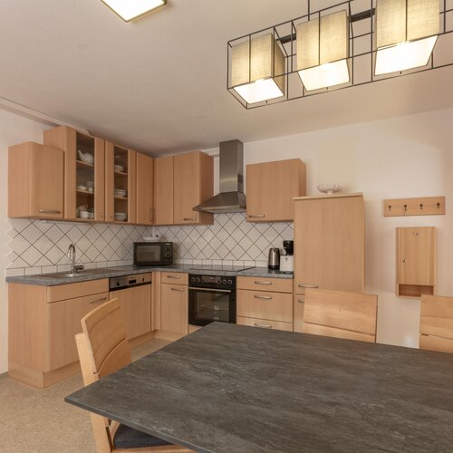 Bright wooden kitchen with cabinets, table, and appliances