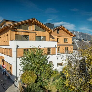 Modern wooden-clad apartment building along street with trees